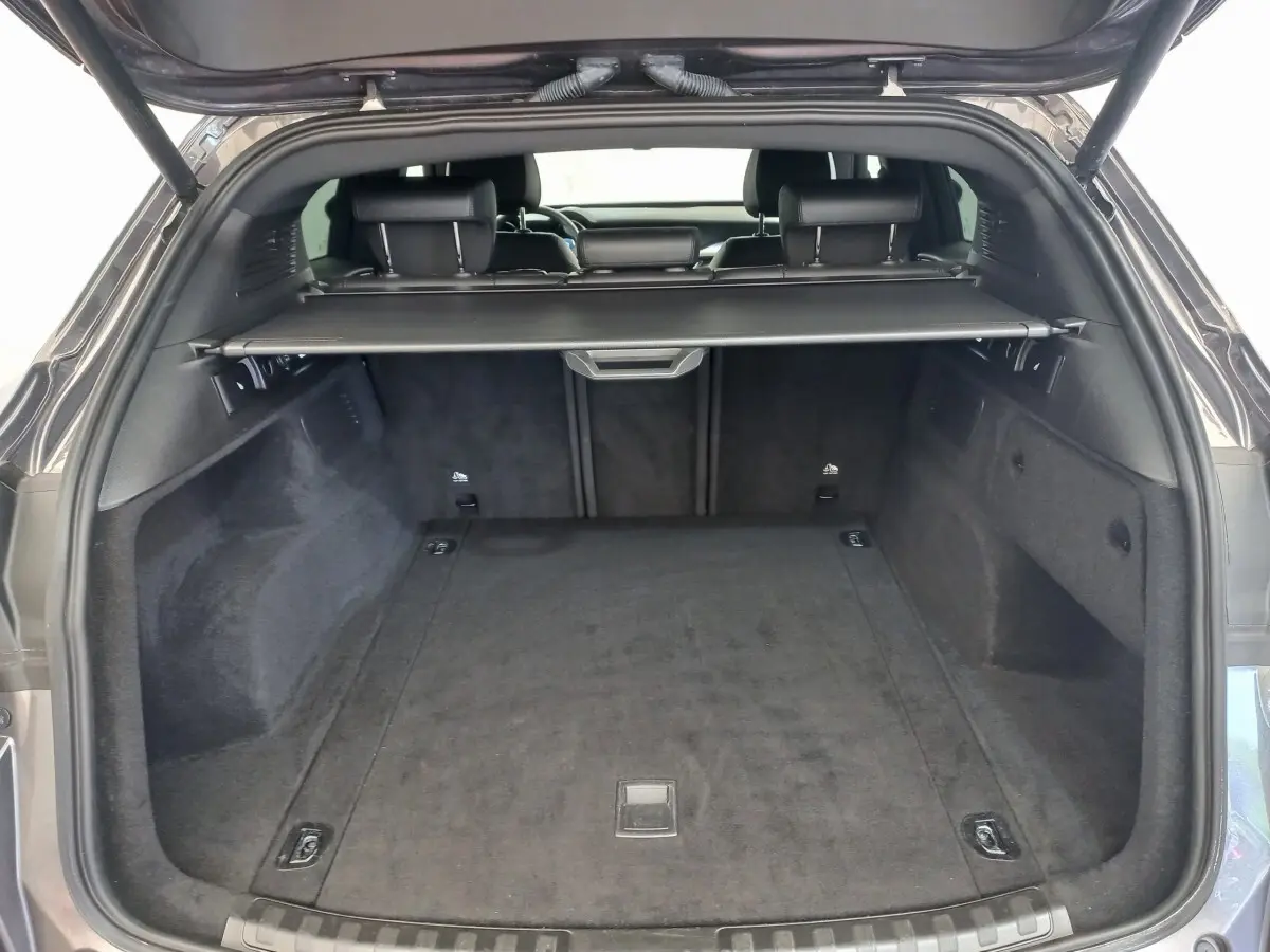 Coffre ouvert vu de l'arrière d'un Alfa Romeo Stelvio gris foncé, avec cache-bagages et banquette arrière visible.