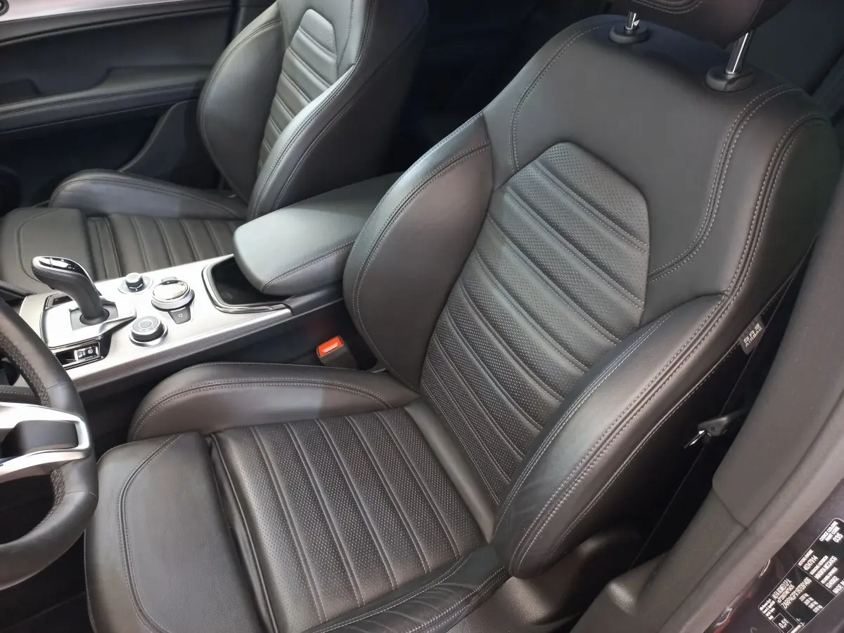 Vue intérieure rapprochée des sièges avant en cuir noir de l'Alfa Romeo Stelvio 2.2 TD 160 AT8 Sprint, avec console centrale visible.