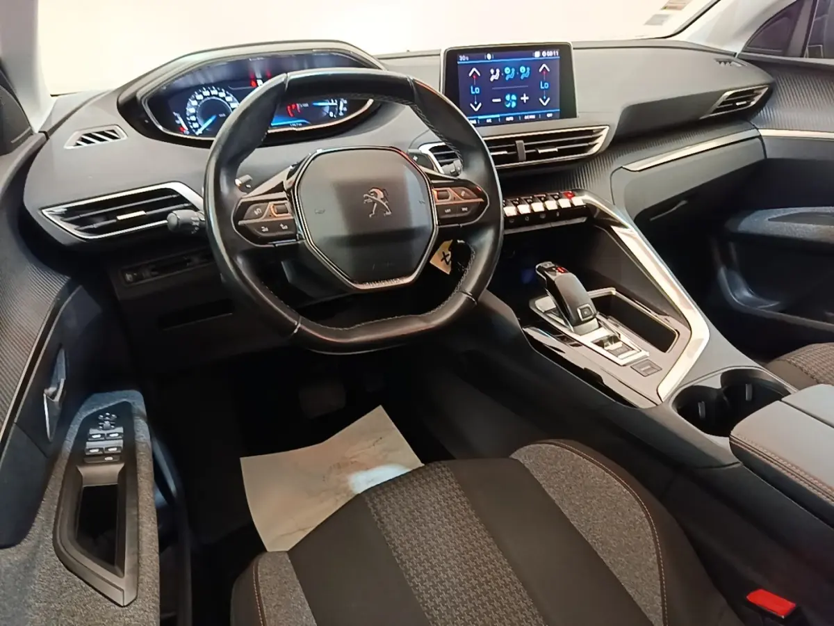 Vue intérieure côté conducteur du Peugeot 3008 noir, volant cuir multifonctions et écran tactile central visible.