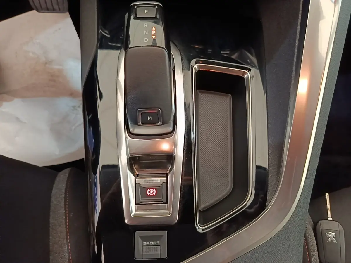 Vue rapprochée de la console centrale noire du Peugeot 3008 avec levier de boîte automatique et bouton sport.