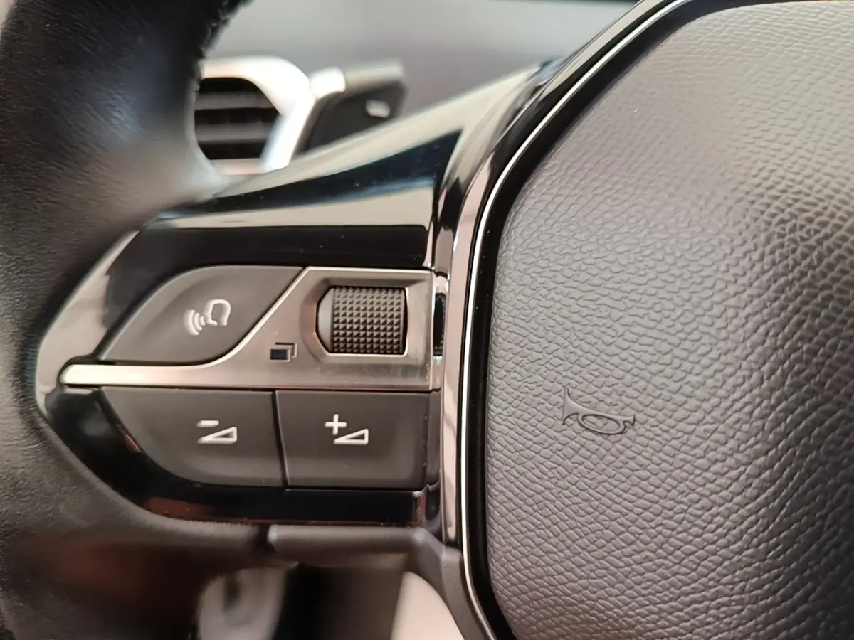 Gros plan sur le volant cuir noir du Peugeot 3008, montrant les commandes multifonctions côté gauche.