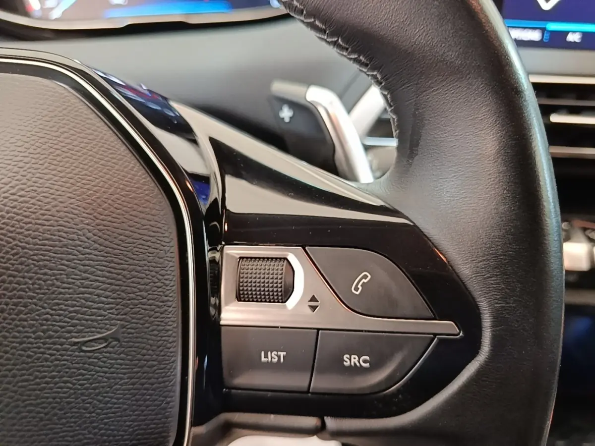 Gros plan sur le volant cuir noir multifonctions du Peugeot 3008, avec commandes audio et téléphone intégrées.
