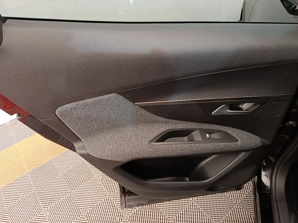 Porte intérieure côté gauche du Peugeot 3008 noir, avec habillage tissu gris et insert imitation carbone.