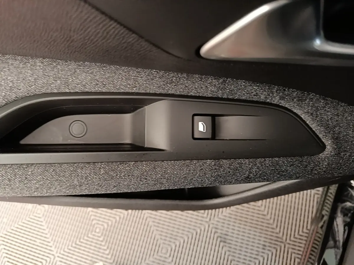 Détail de la commande d'ouverture de la trappe à carburant sur la porte intérieure d'un Peugeot 3008 noir.