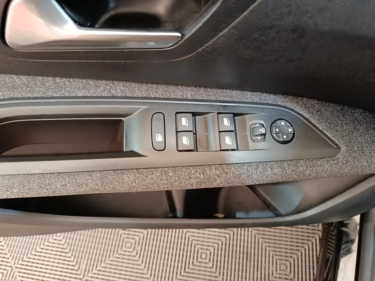 Gros plan sur la commande des vitres et rétroviseurs côté conducteur de la Peugeot 3008 noire, garniture tissu.