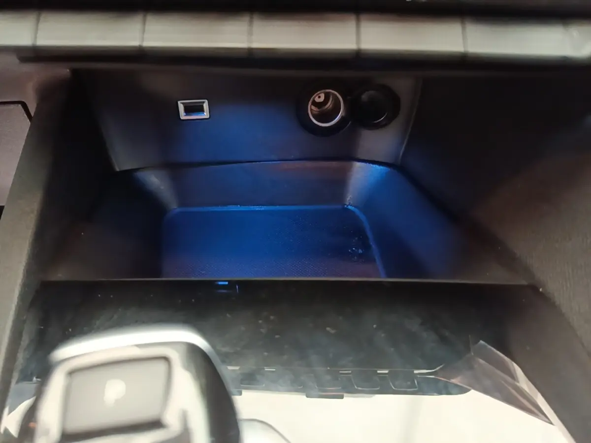 Gros plan sur la console centrale noire du Peugeot 3008, avec prise USB et allume-cigare visibles.