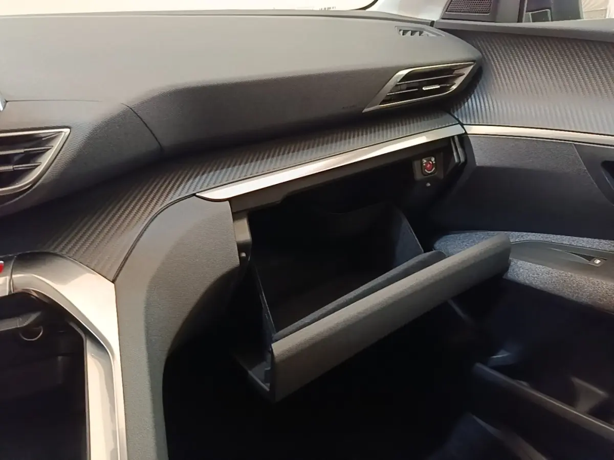 Vue intérieure côté passager du Peugeot 3008 2018 noir, boîte à gants ouverte et tableau de bord avec finition carbone.