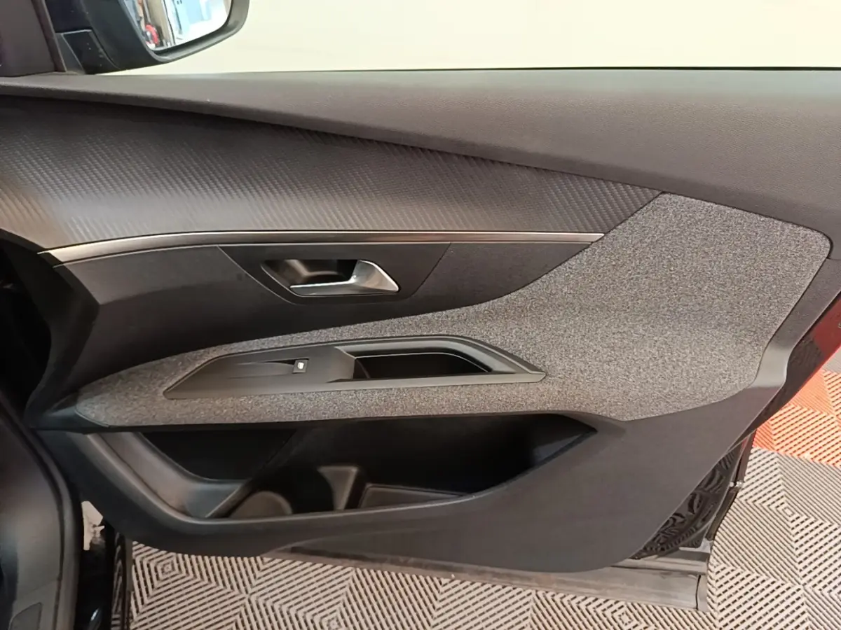 Vue intérieure côté gauche de la porte avant d’un Peugeot 3008 noir avec habillage tissu gris et poignée argentée.