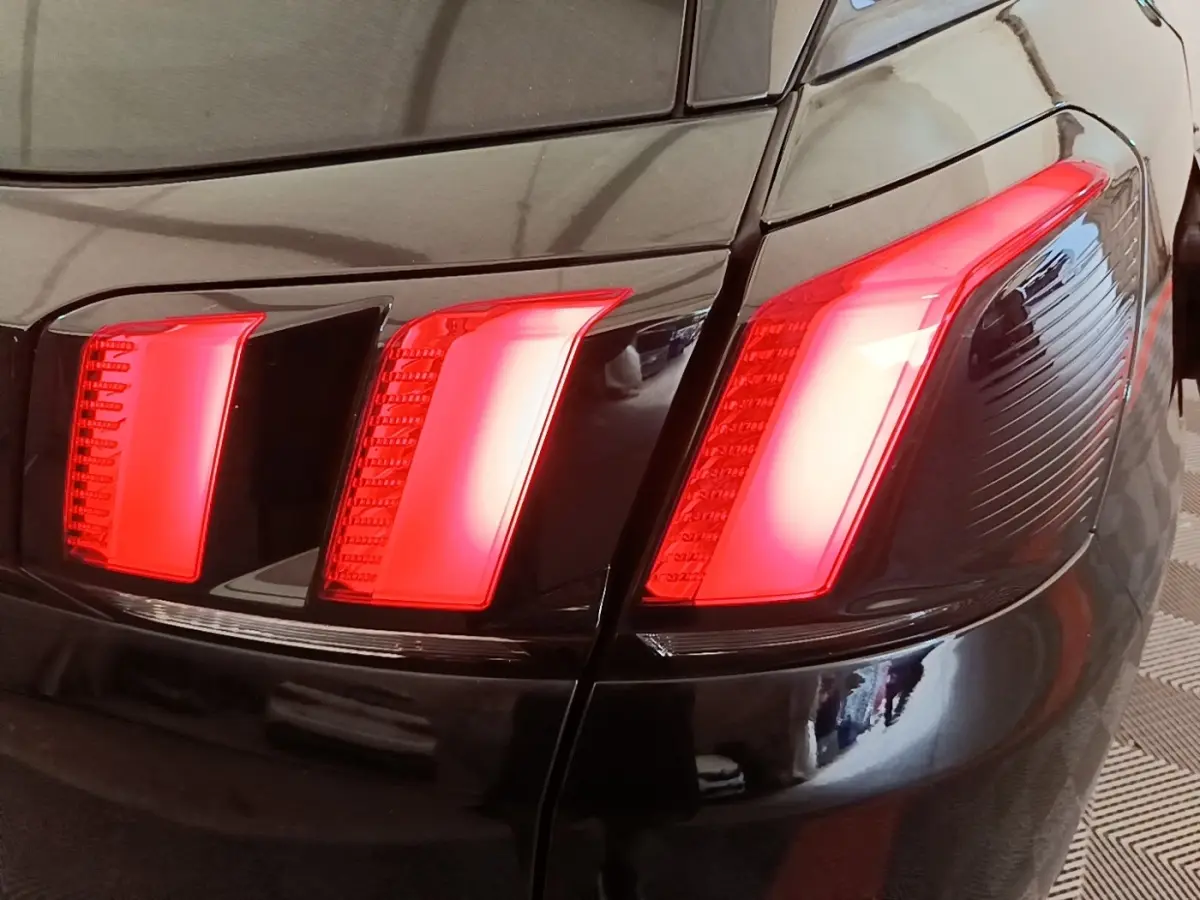 Gros plan sur le feu arrière droit rouge du Peugeot 3008 noir, soulignant la carrosserie brillante.