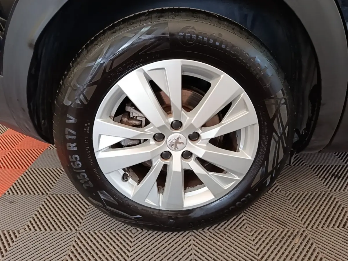 Gros plan sur la jante argentée et le pneu Continental du côté gauche d’un Peugeot 3008 noir.