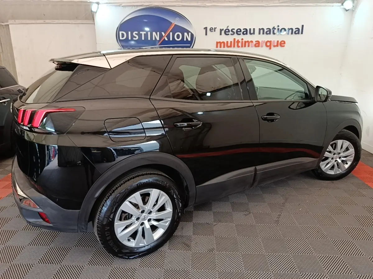 Vue côté droit arrière d’un Peugeot 3008 noir brillant avec feux arrière à griffes LED en intérieur showroom.