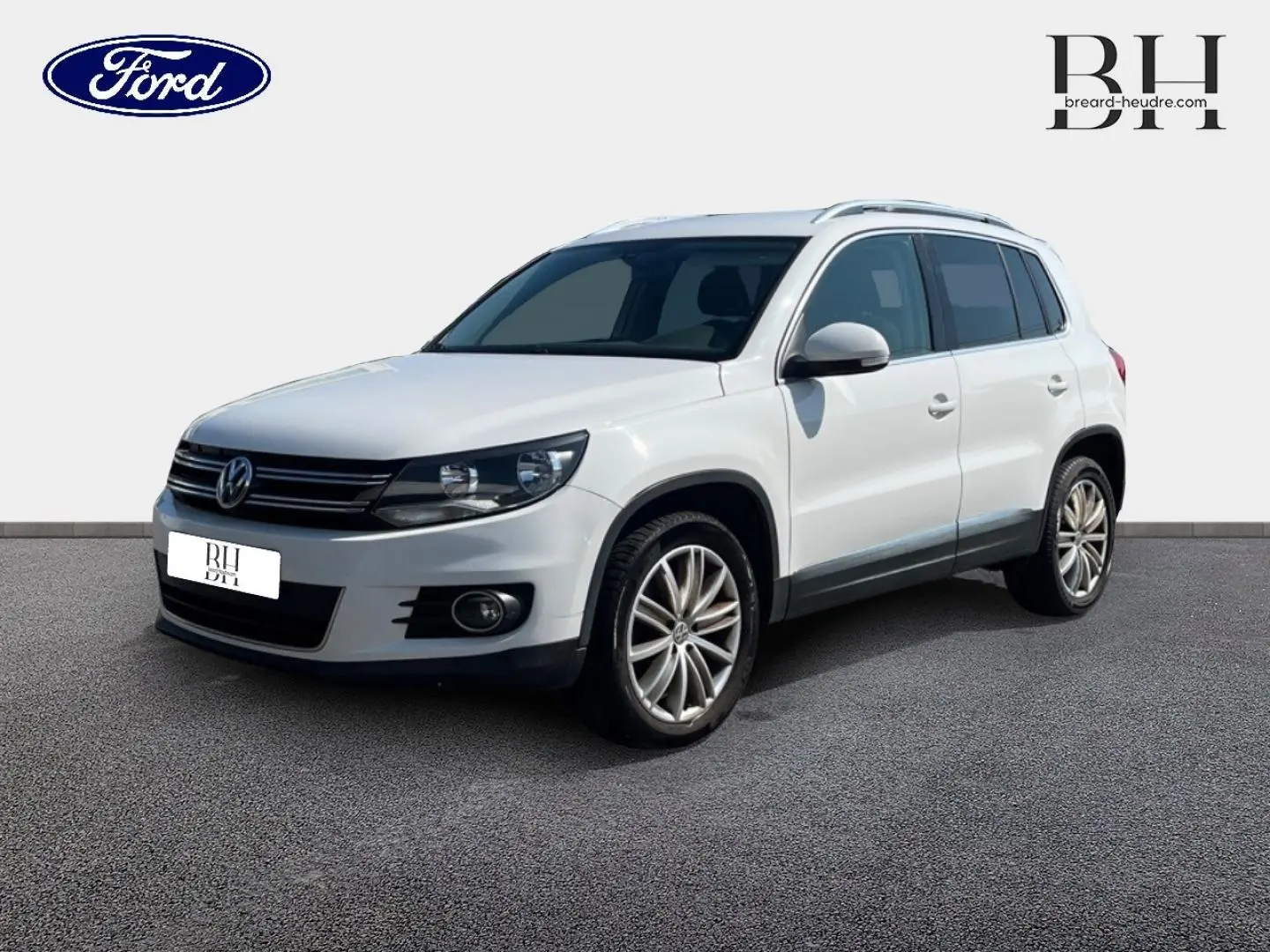 Volkswagen Tiguan blanc Candy en 3/4 avant droit, avec jantes alliage et barres de toit visibles.