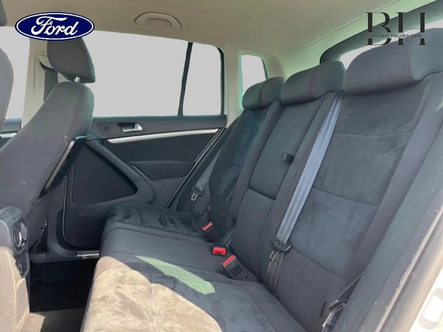 Vue intérieure de la banquette arrière noire du Volkswagen Tiguan 2013, côté droit avec ceintures visibles.