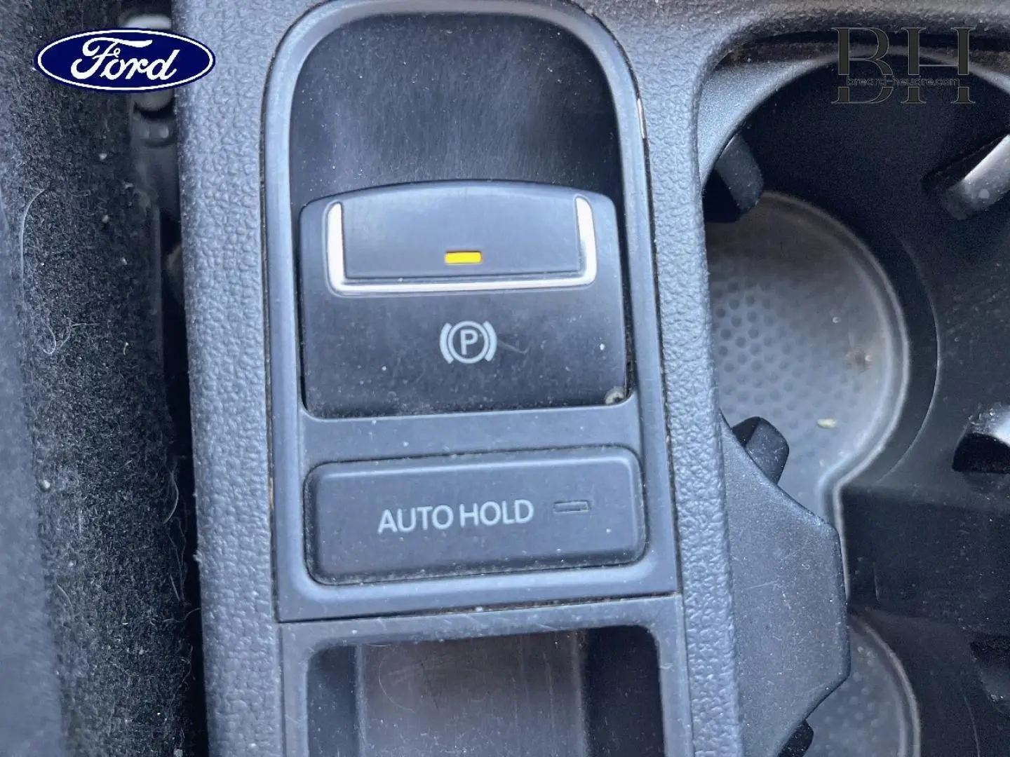 Gros plan sur la commande de frein de stationnement électrique et bouton Auto Hold dans un intérieur de voiture.