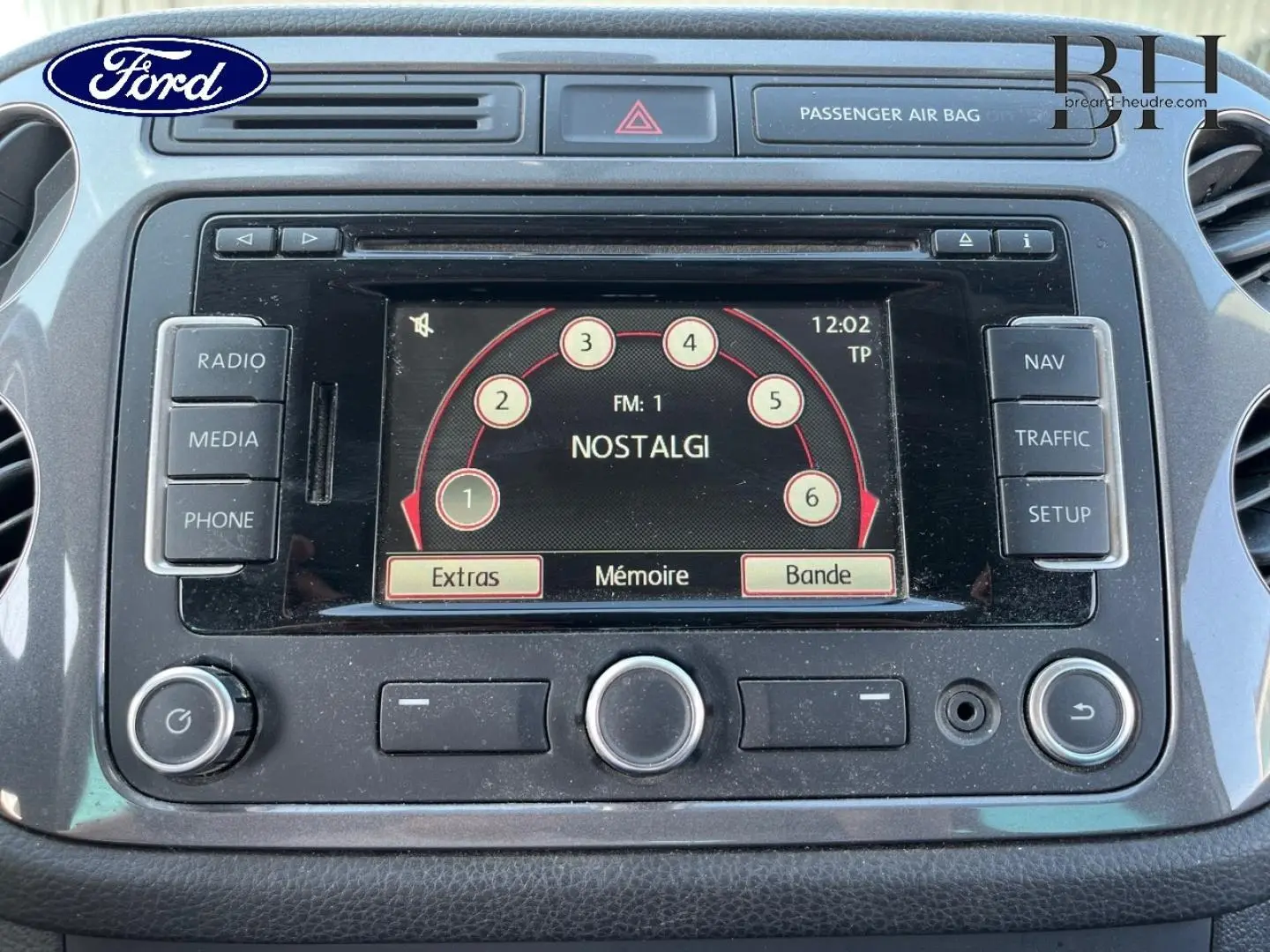 Tableau de bord noir avec écran tactile central affichant la radio, dans un Volkswagen Tiguan blanc Candy 2013.