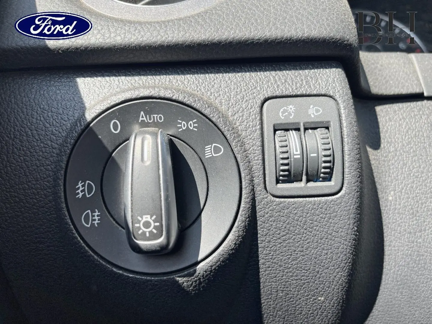 Image montrant le tableau de bord d'une Ford avec commandes d'éclairage et réglages de phares en gros plan.