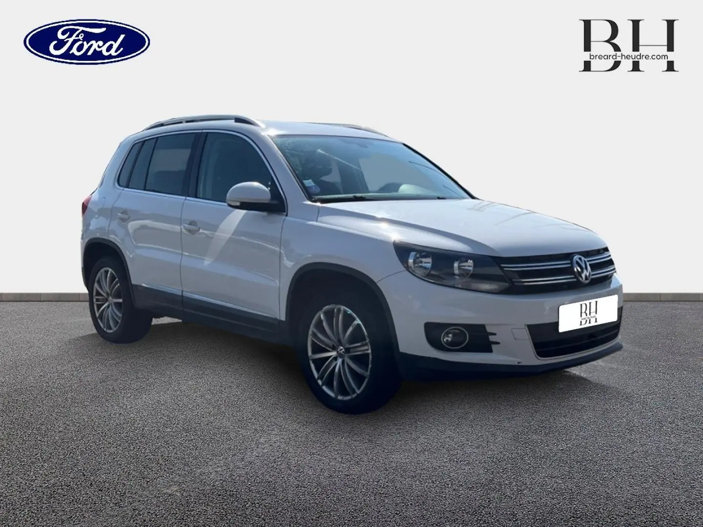 Volkswagen Tiguan blanc Candy vu en 3/4 avant droit avec jantes alu 17 pouces et barres de toit.