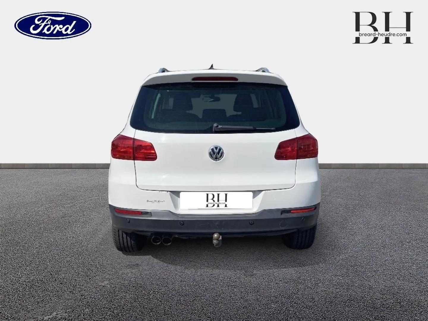 Vue arrière d'un Volkswagen Tiguan blanc Candy de 2013 avec attelage et feux arrière rouges sur sol gris.