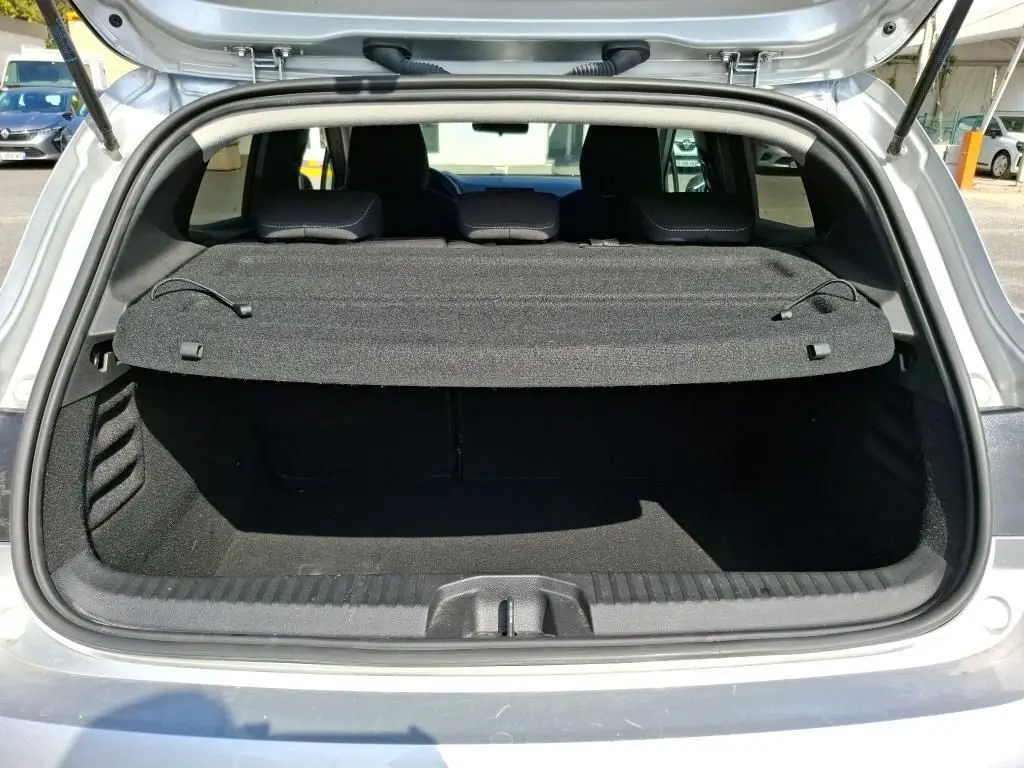 Coffre ouvert vu de l'arrière d'une Renault Clio gris platine 2023, avec cache-bagages en place.