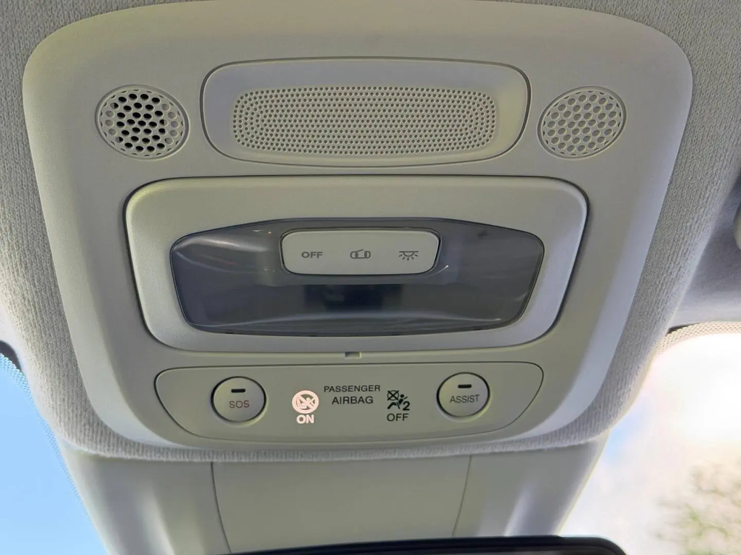 Vue intérieure en gros plan du plafonnier gris clair avec boutons SOS et Assist sur Fiat 500 électrique 2024.