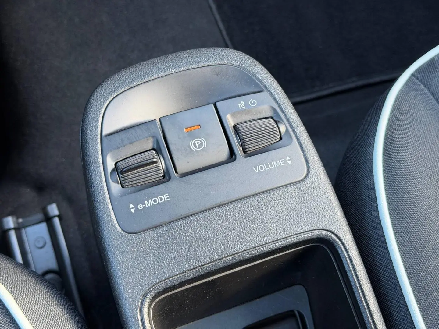 Gros plan sur la console centrale noire de la Fiat 500 e 118ch MY24 avec commandes e-Mode, frein électrique et réglage volume.
