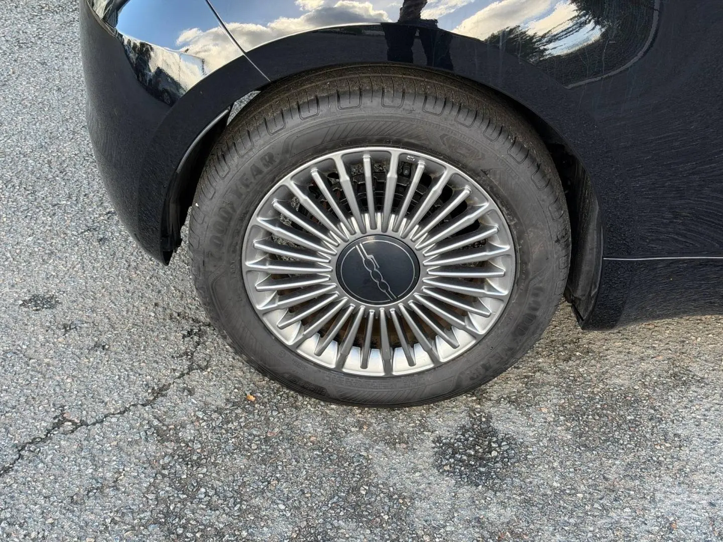Gros plan sur la roue arrière droite de la Fiat 500 e 118ch MY24 en Onyx Black pastel avec jante argentée stylisée.