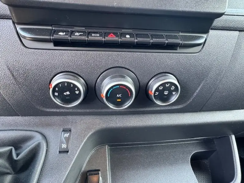 Détail du tableau de bord du Renault Master Combi blanc, montrant les commandes de climatisation et les boutons de fonction.