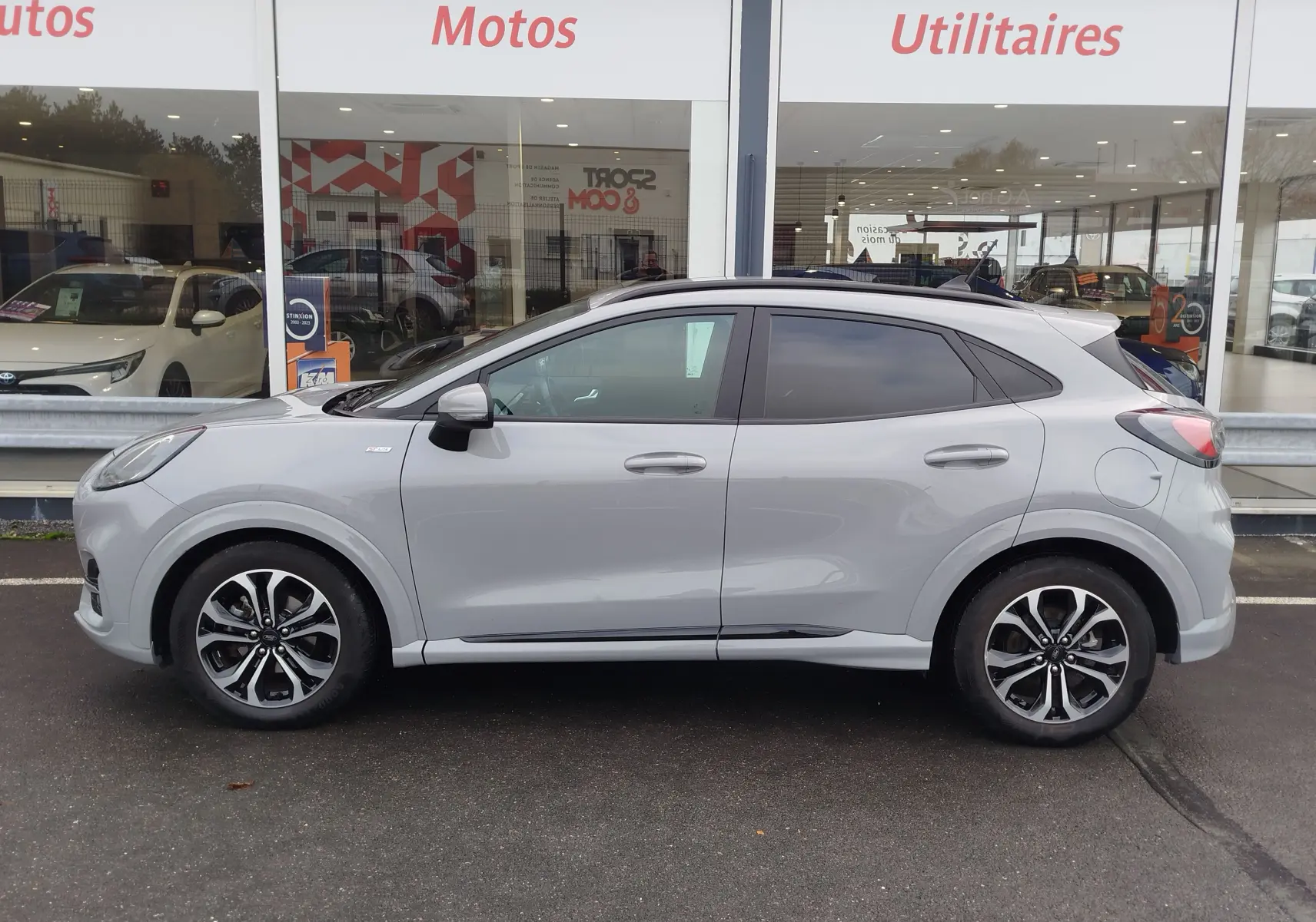 Vue de profil côté gauche du Ford Puma 1.0 EcoBoost gris Fashion Matter avec toit noir et vitres teintées.