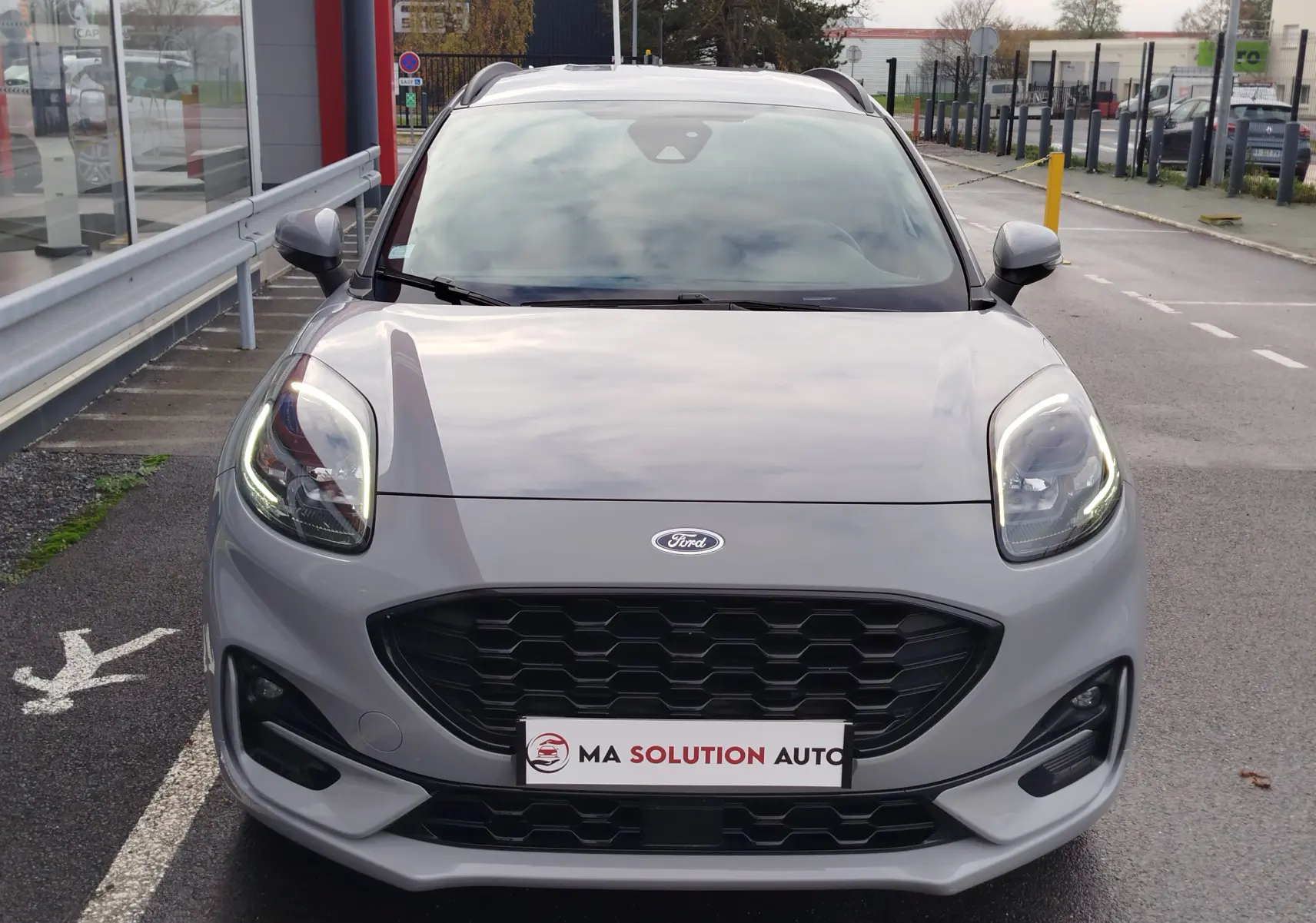 Vue frontale d'une Ford Puma 1.0 EcoBoost gris Fashion avec calandre noire et phares LED allumés.