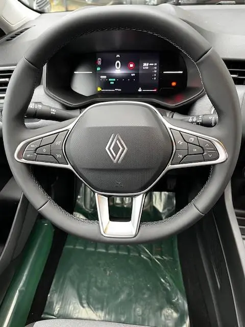 Vue rapprochée du volant cuir synthétique de la Renault Clio 2025 avec commandes multifonctions et combiné d'instruments numérique.