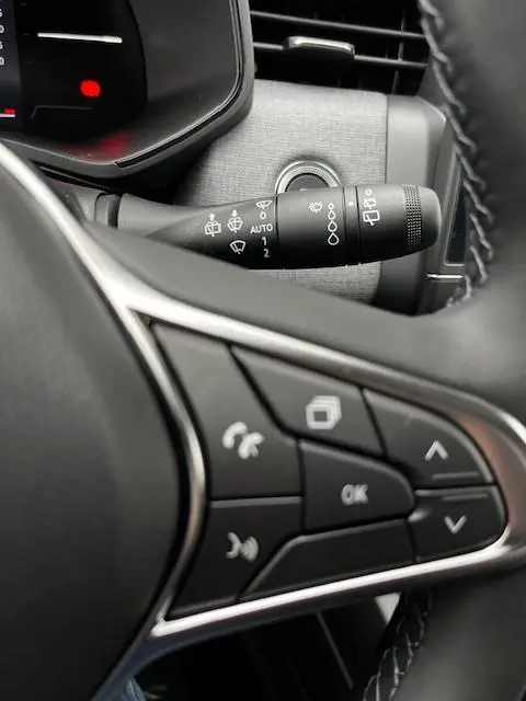 Gros plan sur les commandes au volant et le commodo d'essuie-glace d'une Renault Clio noire, version Evolution Blue dCi 100.