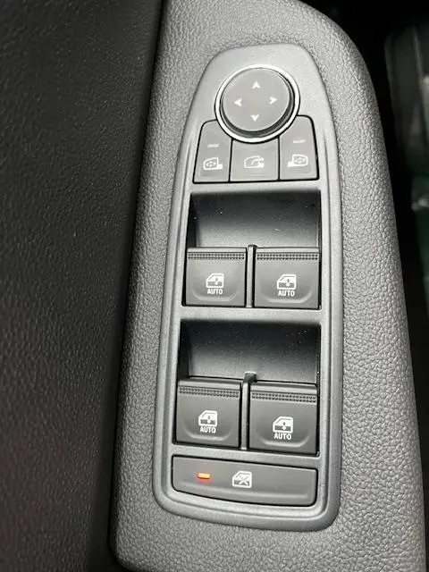 Vue rapprochée des commandes de lève-vitres et rétroviseurs sur la porte côté conducteur d’une Renault Clio noire 2025.