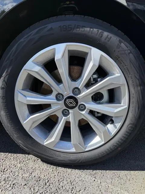 Gros plan sur la roue avant gauche d’une Renault Clio noire, mettant en valeur la jante alliage argentée au design moderne.