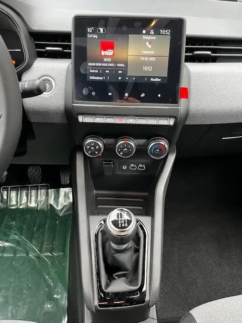 Vue intérieure centrée sur la console centrale et levier de vitesse manuel de la Renault Clio noire Evolution Blue dCi 2025.