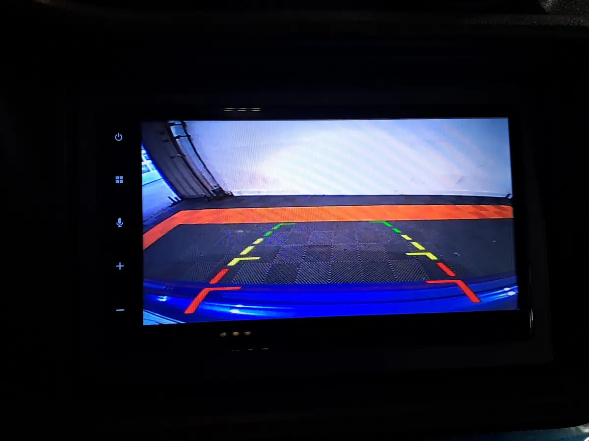 Vue caméra de recul montrant l’arrière bleu de l’AIXAM AMBITION 0.5 CITY GTO avec repères de stationnement colorés.