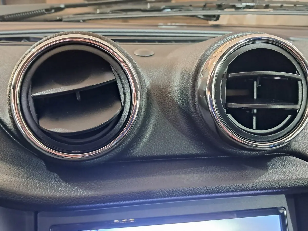 Gros plan sur les deux aérateurs ronds chromés du tableau de bord d’une Aixam Ambition bleu 2026.