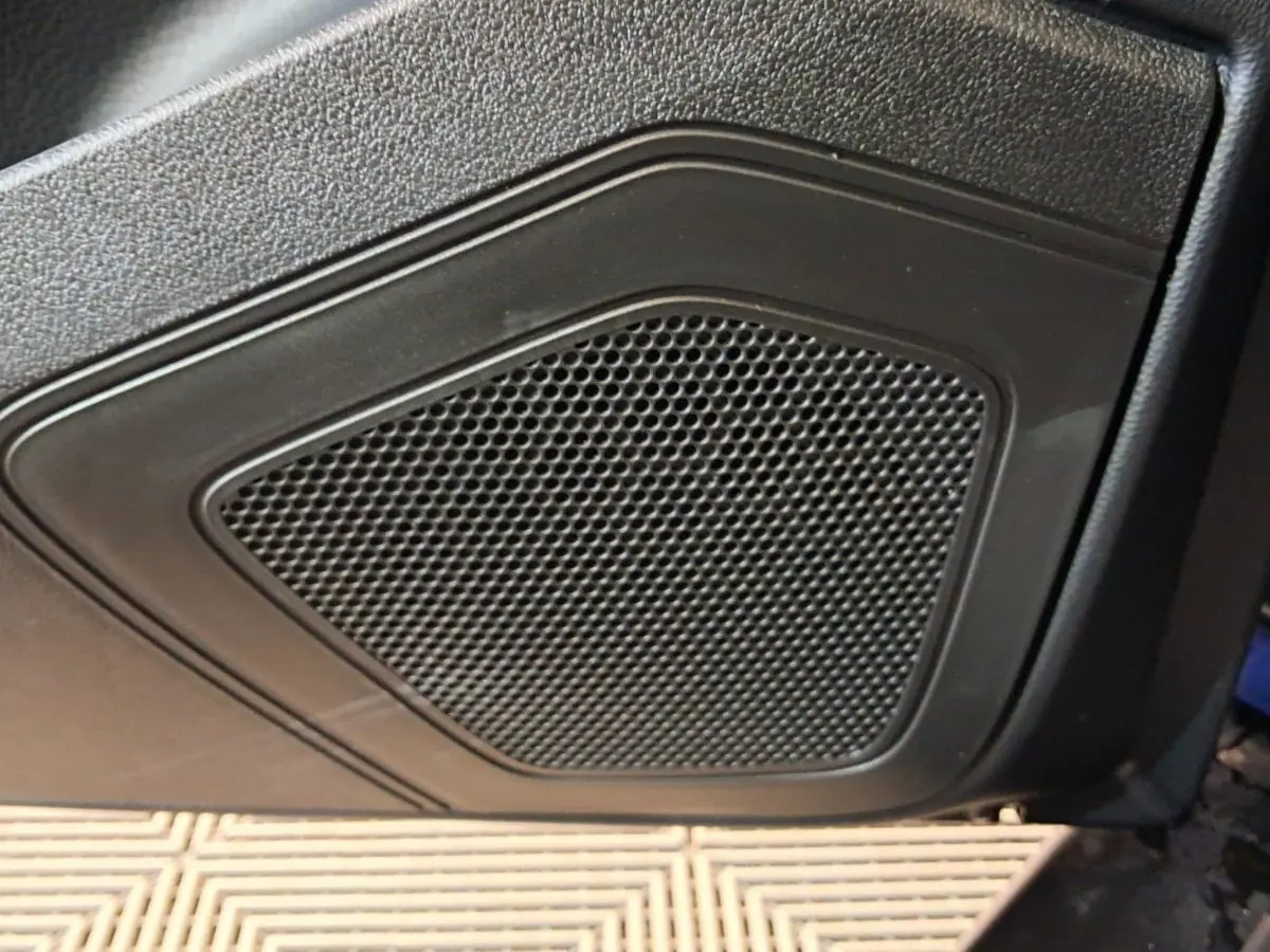 Gros plan sur le haut-parleur intégré à la porte côté conducteur d’une Aixam Ambition bleu 2026.