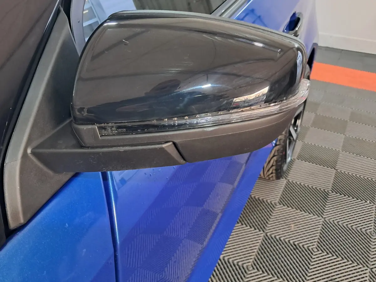 Gros plan sur le rétroviseur extérieur côté conducteur noir avec caméra, sur une Aixam Ambition bleu vue de profil.