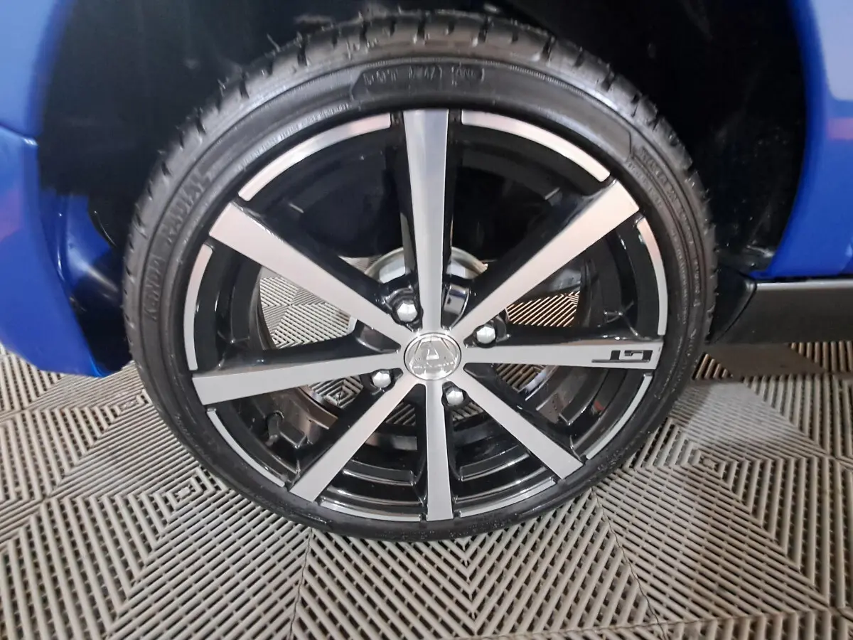 Gros plan sur la jante noire et argentée avec logo AIXAM d'une Aixam Ambition bleu, côté roue avant.