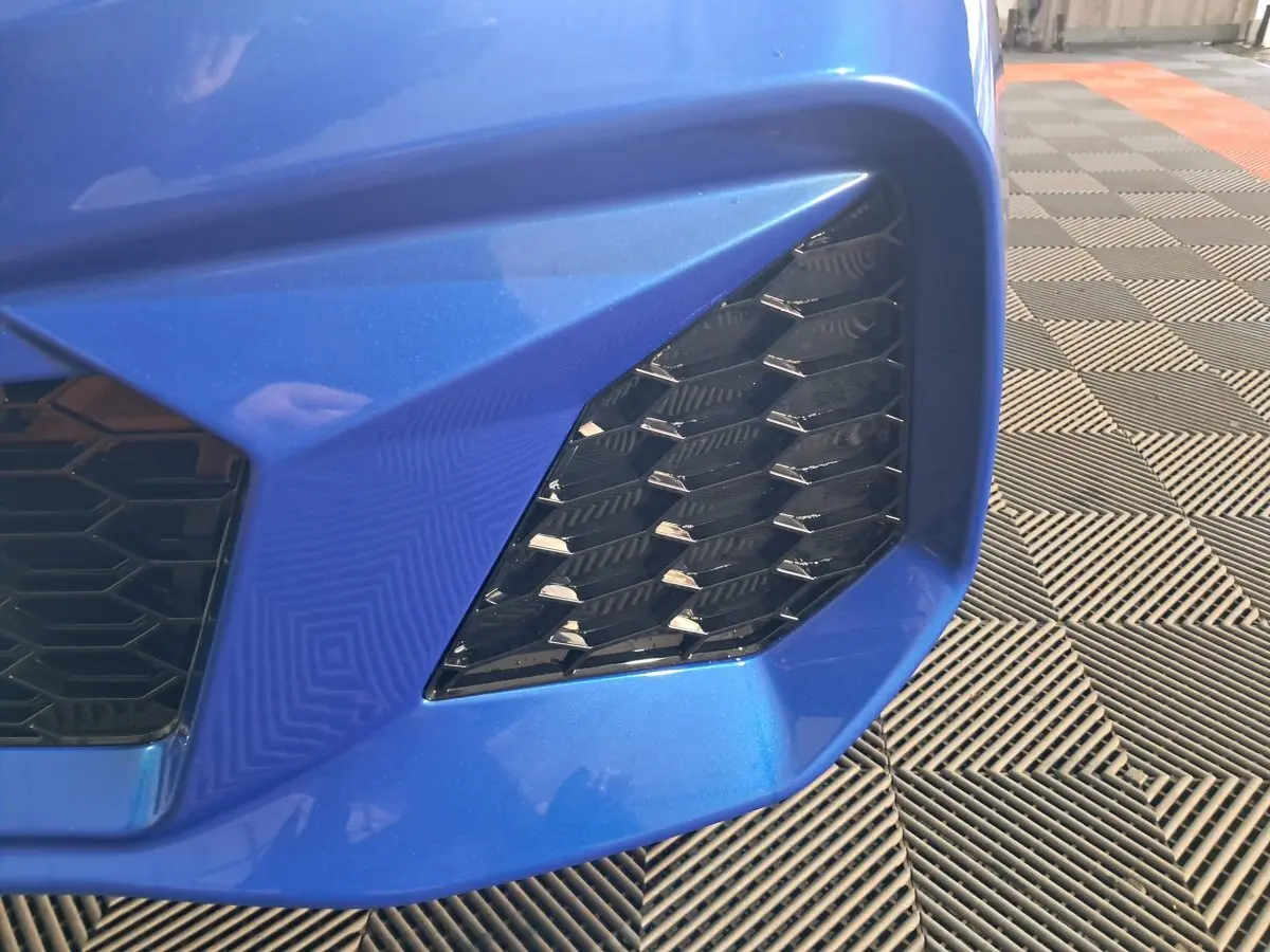 Gros plan sur la calandre avant droite bleue de l'AIXAM AMBITION 0.5 CITY GTO avec motif hexagonal noir.