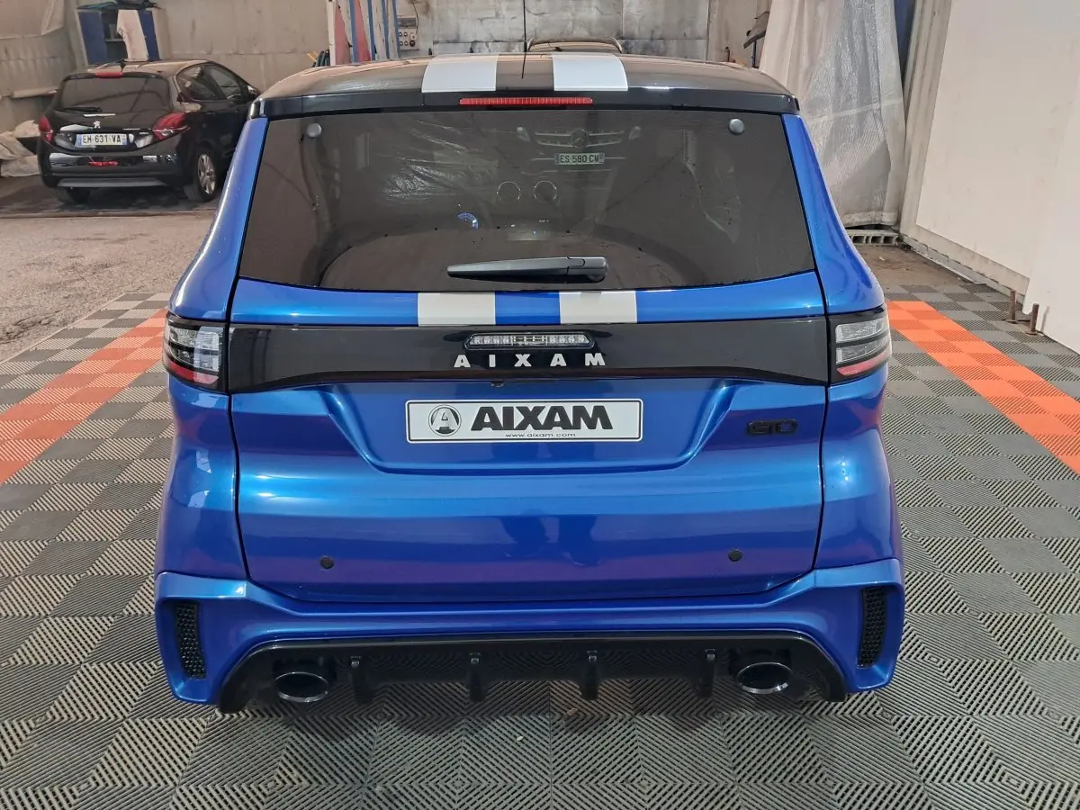 Vue arrière d'une AIXAM AMBITION 0.5 CITY GTO bleu avec bandes blanches et logo GTO sur fond noir.
