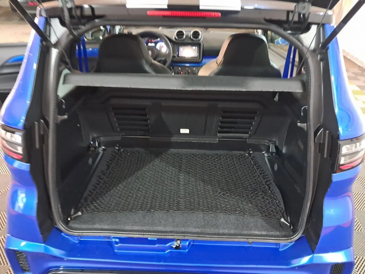 Coffre ouvert vu de l'arrière d'une AIXAM AMBITION bleu 2026 avec intérieur noir et filet de rangement.