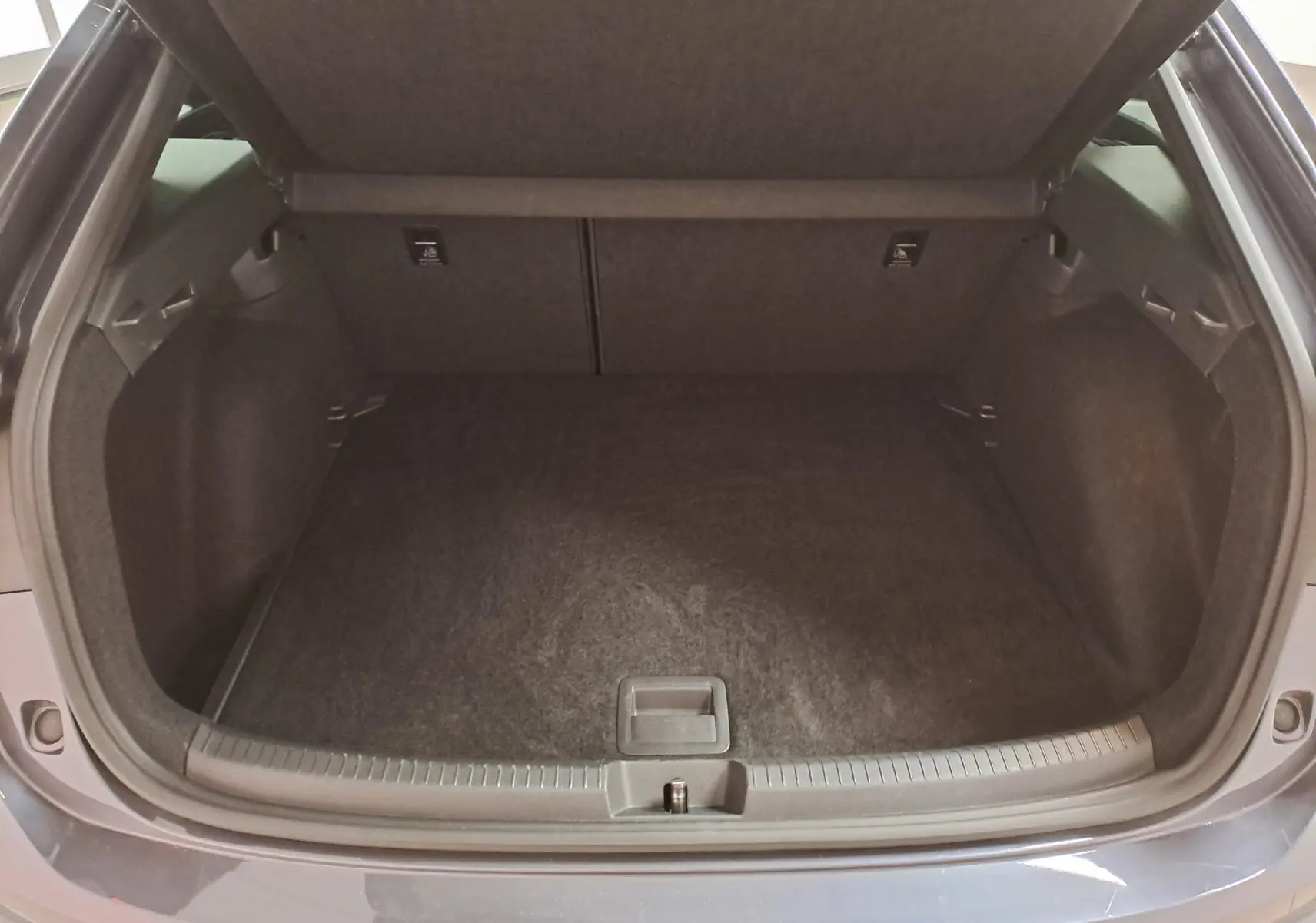 Coffre ouvert vu de l'arrière d'un Volkswagen Taigo gris cendré 2025, finition R-Line avec intérieur noir.