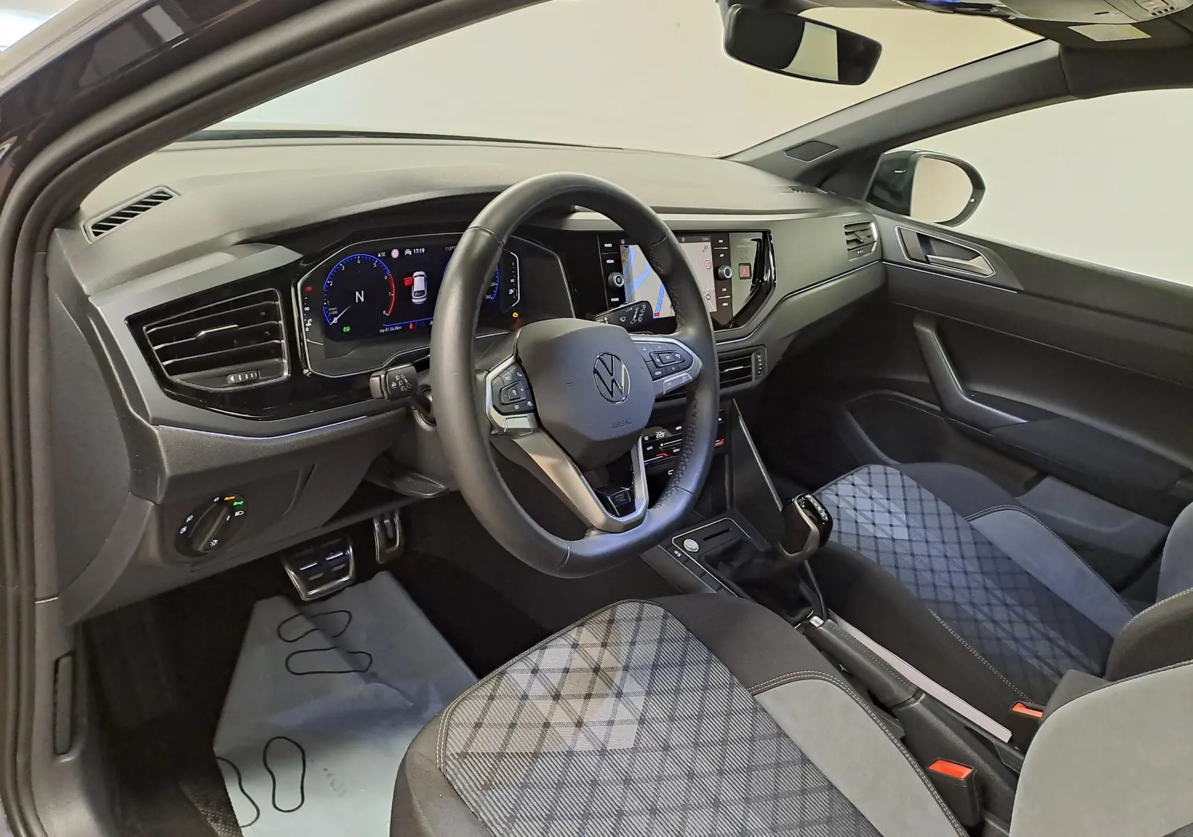 Vue intérieure côté conducteur du Volkswagen Taigo 1.5 TSI 150 DSG7 R-Line Edition avec sièges tissu gris à motifs.