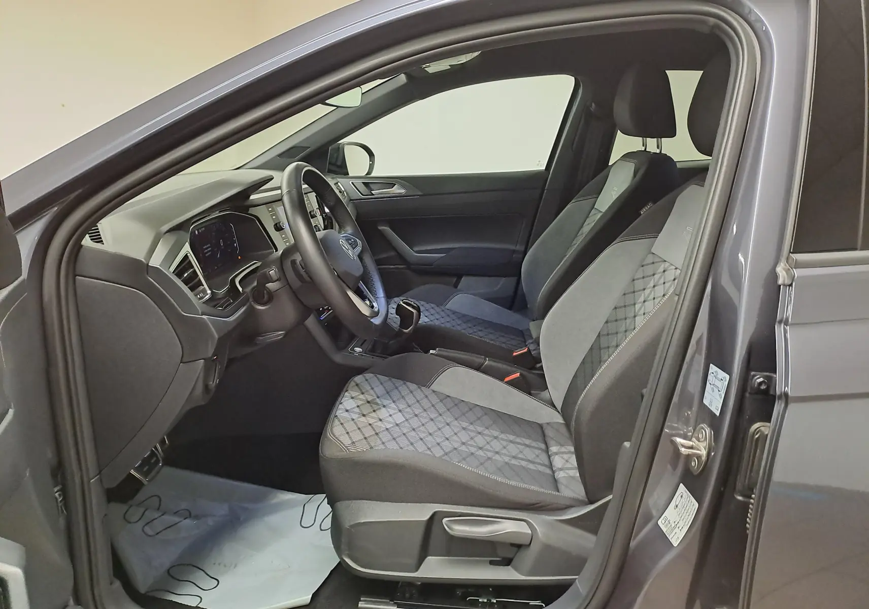 Vue intérieure côté conducteur du Volkswagen Taigo 1.5 TSI 150 DSG7 R-Line Edition gris cendré, sièges tissu à motifs géométriques.