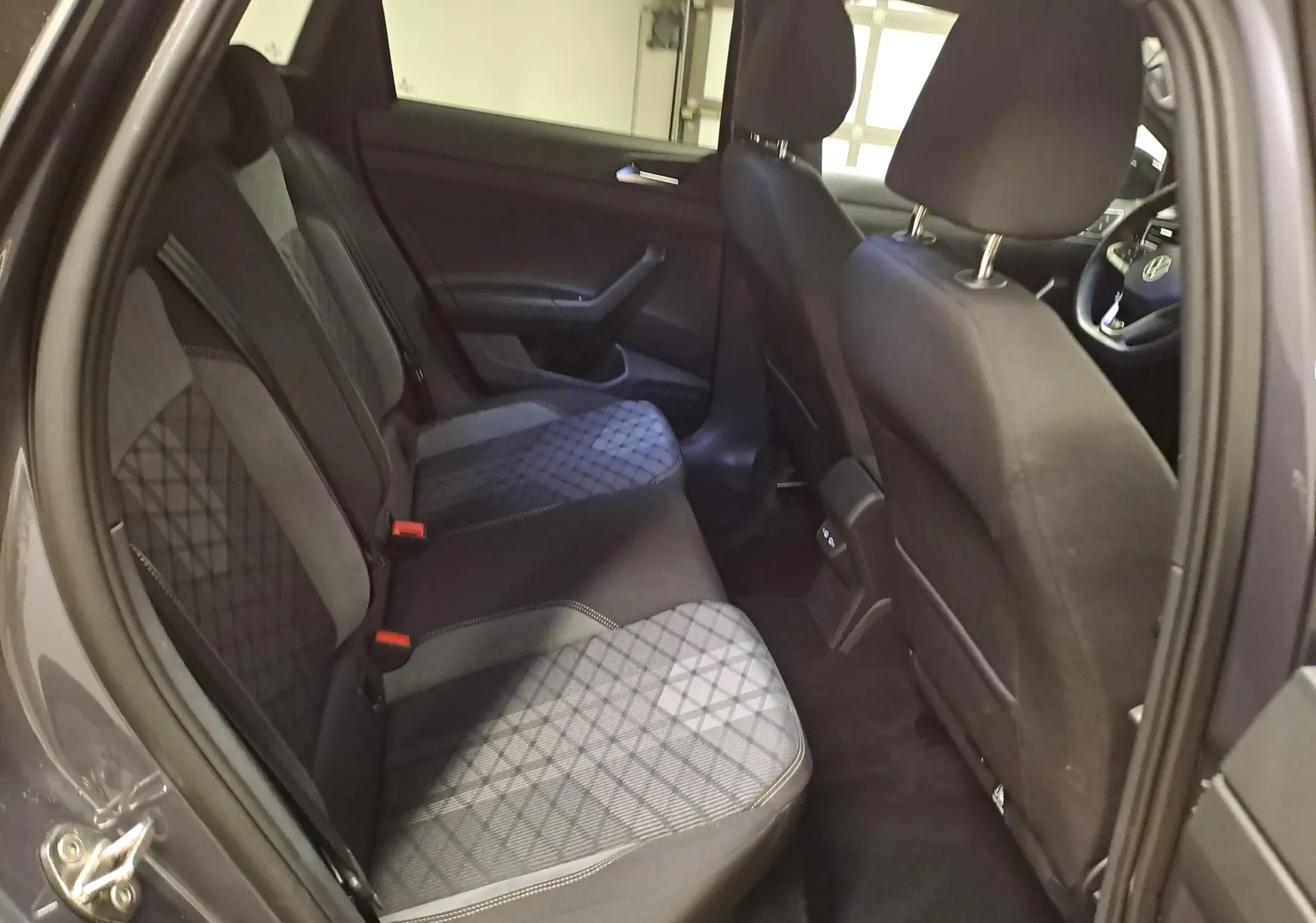 Vue intérieure côté gauche des sièges arrière en tissu gris à motif losange du Volkswagen Taigo 1.5 TSI 150 DSG7 R-Line Edition.