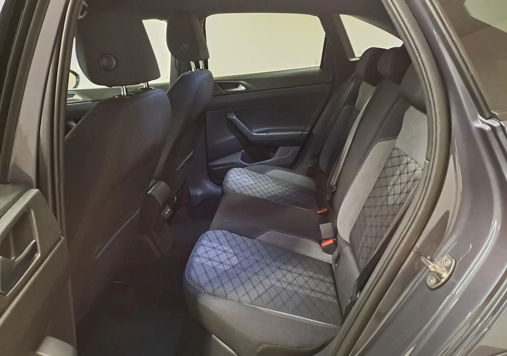 Vue intérieure côté droit des sièges arrière du Volkswagen Taigo 2025, tissu gris à motif losanges et portes assorties.