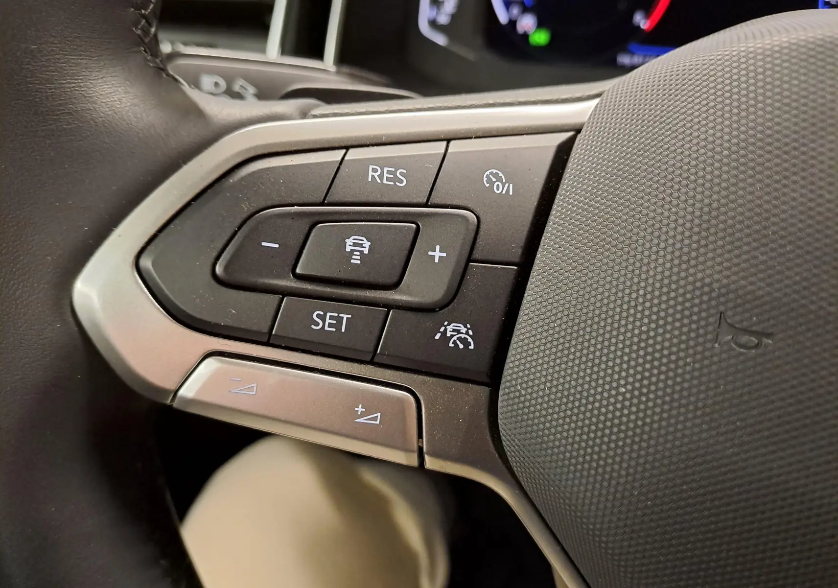 Gros plan sur les commandes au volant du Volkswagen Taigo 1.5 TSI R-Line 2025, boutons de régulateur de vitesse et assistance.