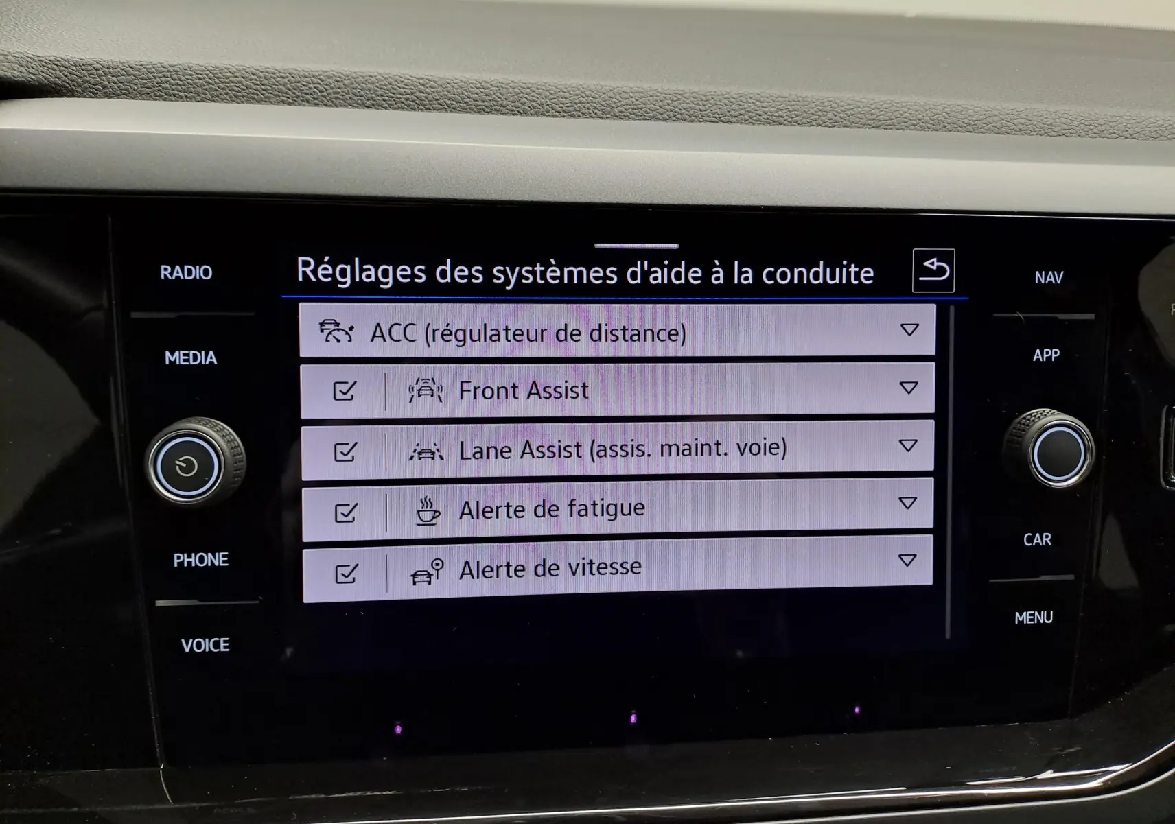 Écran tactile intérieur du Volkswagen Taigo 2025 affichant les réglages des aides à la conduite, boutons autour de l'écran.