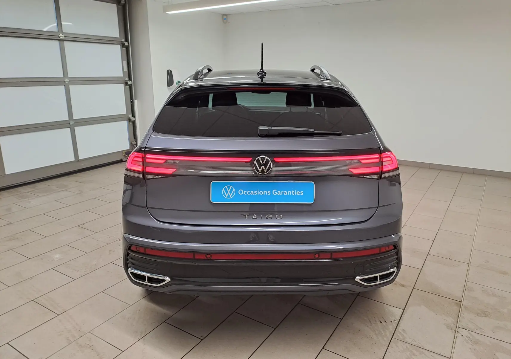 Vue arrière du Volkswagen Taigo 1.5 TSI 150 DSG7 R-Line Edition 2025 en gris cendré avec toit noir et feux LED allumés.
